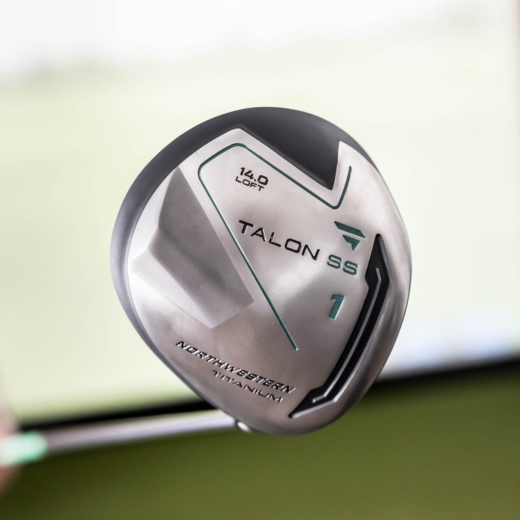 Golf club head with 'Talon S6' branding on a blurred green background